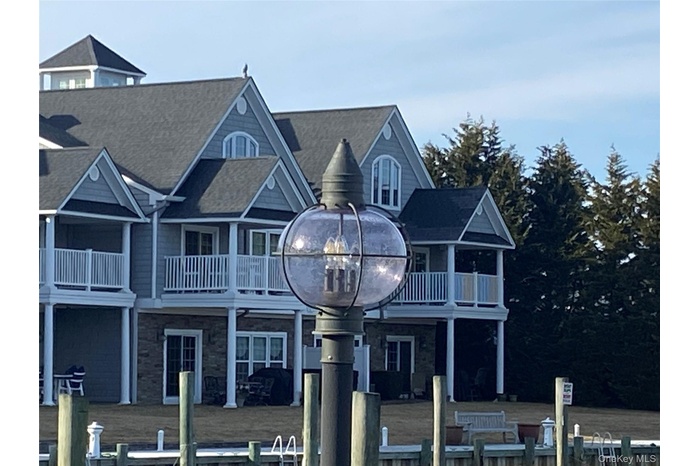 View of front of property with stone siding, a balcony, and a patio area