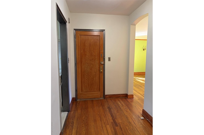 Hallway featuring wood finished floors and arched walkways
