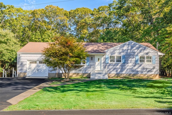 Ranch-style house with a front lawn, driveway, a garage, and roof with shingles
