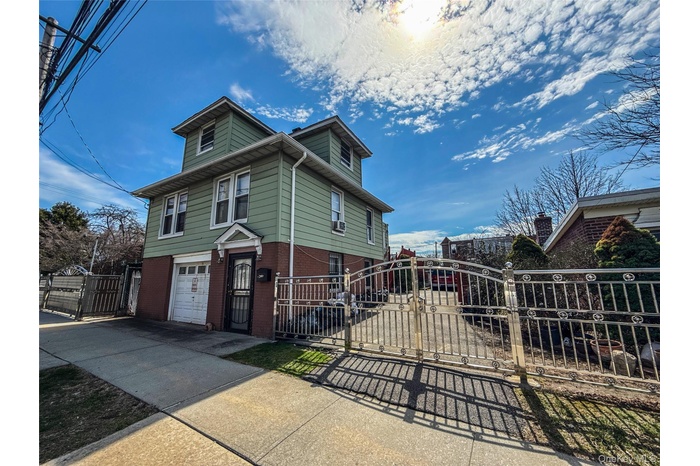 View of front of house with a gate, concrete driveway, fence, an attached garage, and brick siding