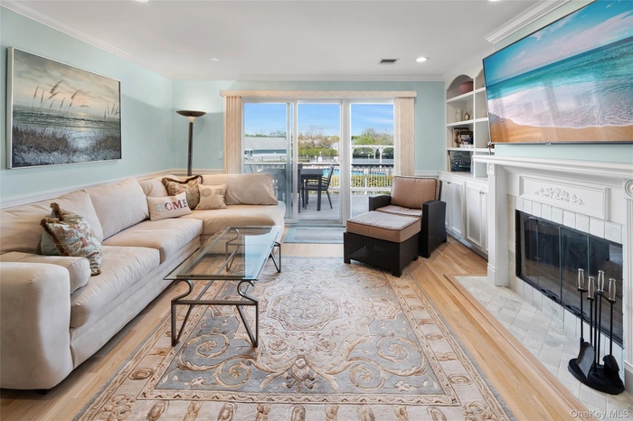 Living room featuring recessed lighting, light wood finished floors, visible vents, crown molding, and a fireplace