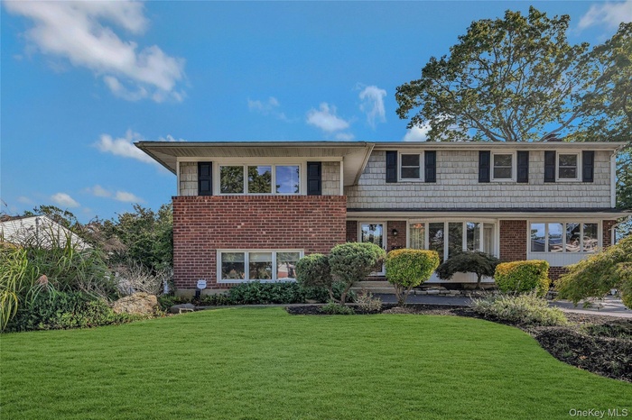 Tri-level home with a front lawn and brick siding