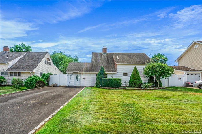 View of front of property featuring a chimney, asphalt driveway, and a gate