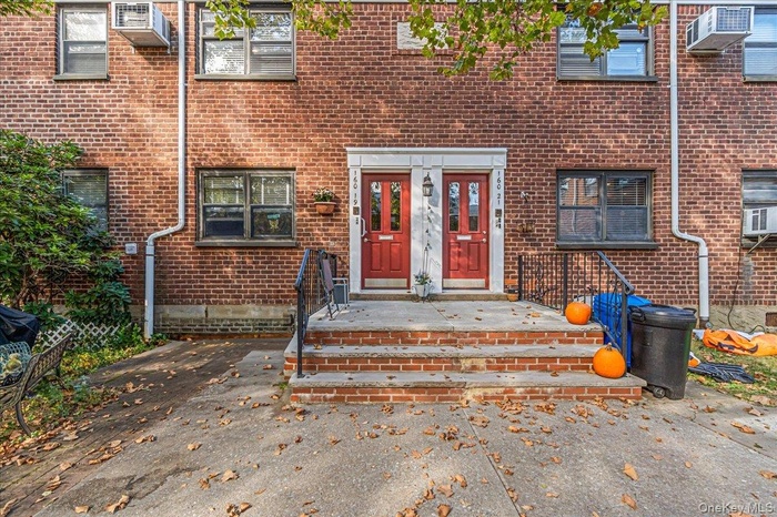 Entrance to property featuring brick siding and a wall unit AC