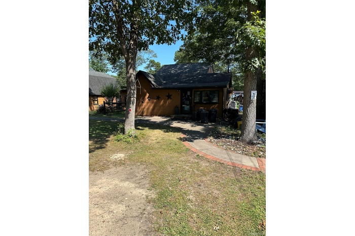 Back of house featuring a lawn and roof with shingles