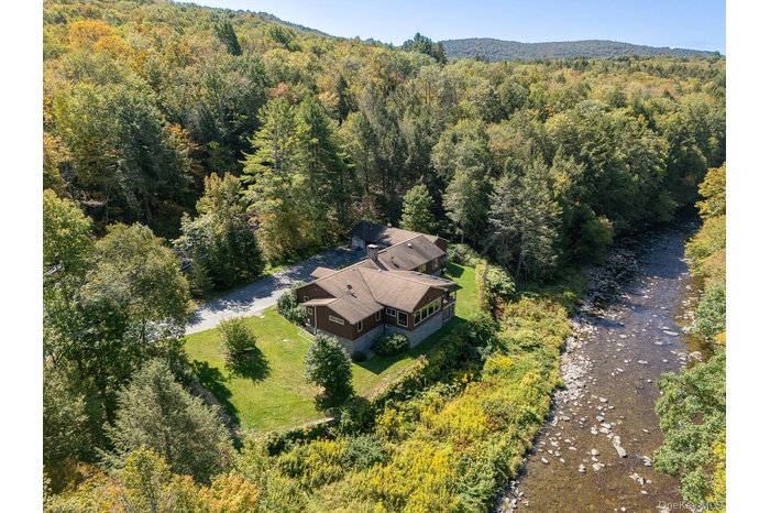 Aerial view of property and surrounding area with a forest
