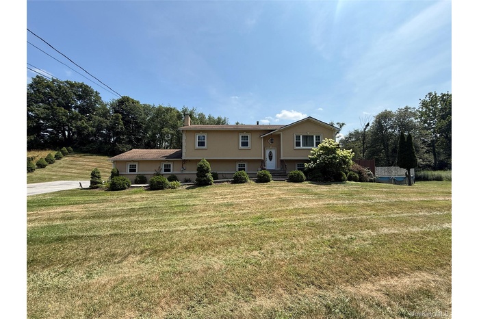 Split foyer home featuring a front lawn and a chimney