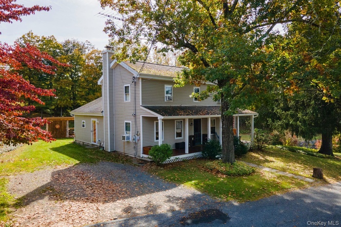 View of front facade with a front yard, covered porch, and a chimney