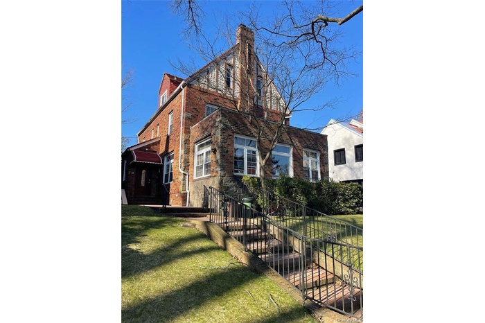 View of side of property featuring a chimney and brick siding