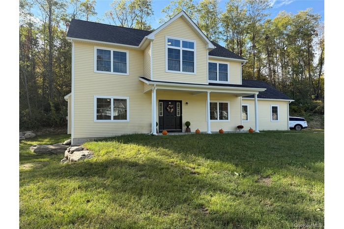Traditional home with a porch, a front lawn, and a shingled roof
