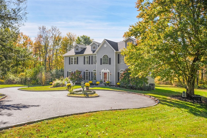 View of front of home with a front yard and curved driveway