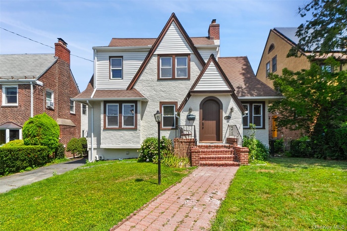 Tudor house featuring a front lawn and roof with shingles