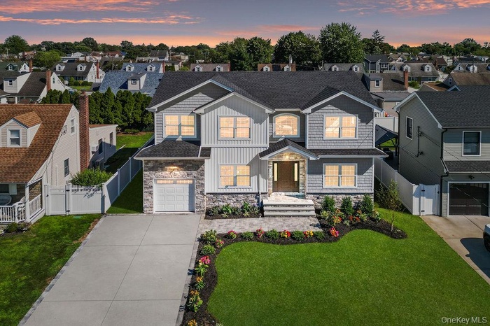 View of front of property with a residential view, roof with shingles, concrete driveway, and stone siding