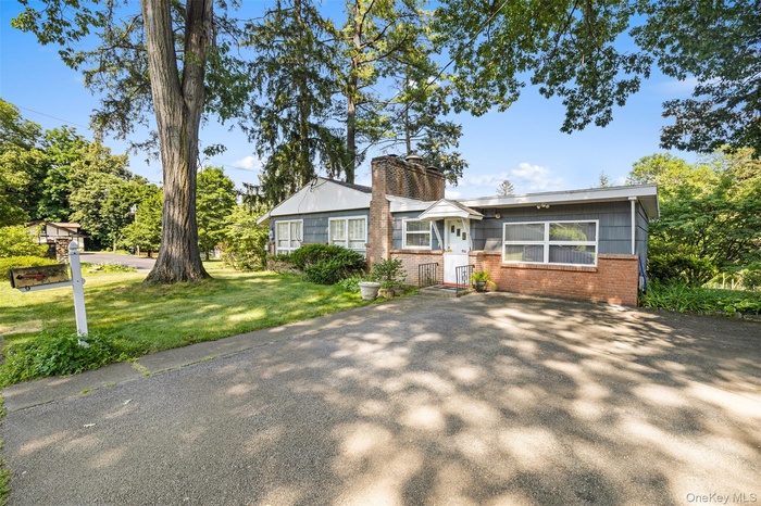 View of front of home with brick siding, a chimney, and a front yard