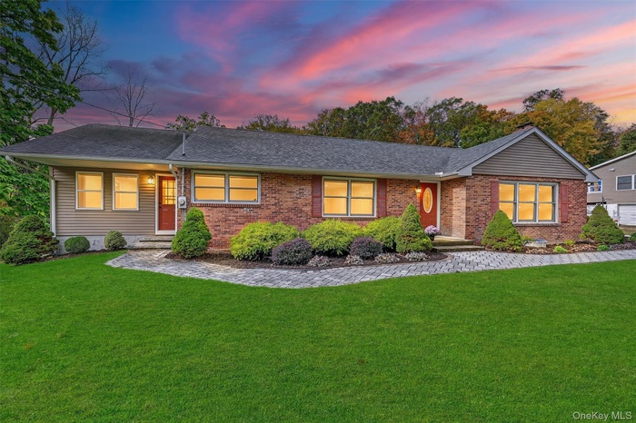 Ranch-style home featuring a lawn, roof with shingles, and brick siding