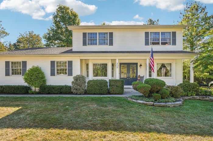 Traditional-style home featuring a porch, a front yard, and french doors