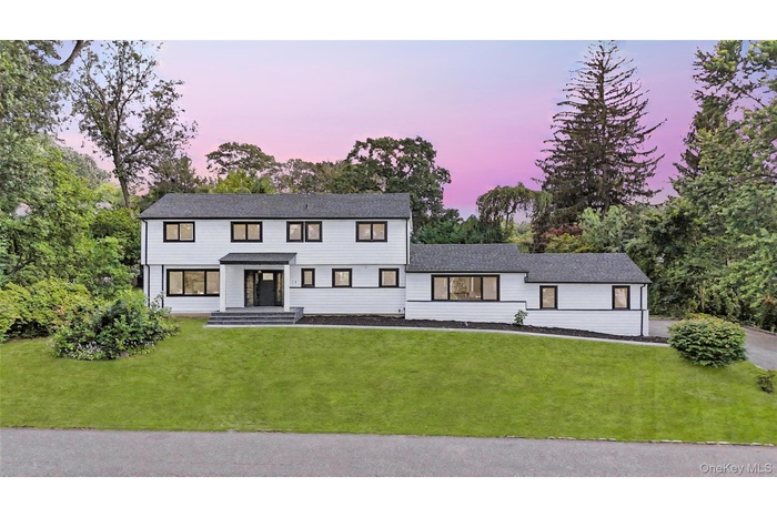 Modern farmhouse with a front lawn and view of wooded area