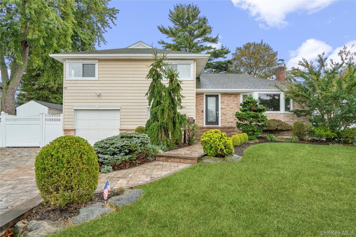 View of front of property featuring a chimney, brick siding, a garage, and roof with shingles