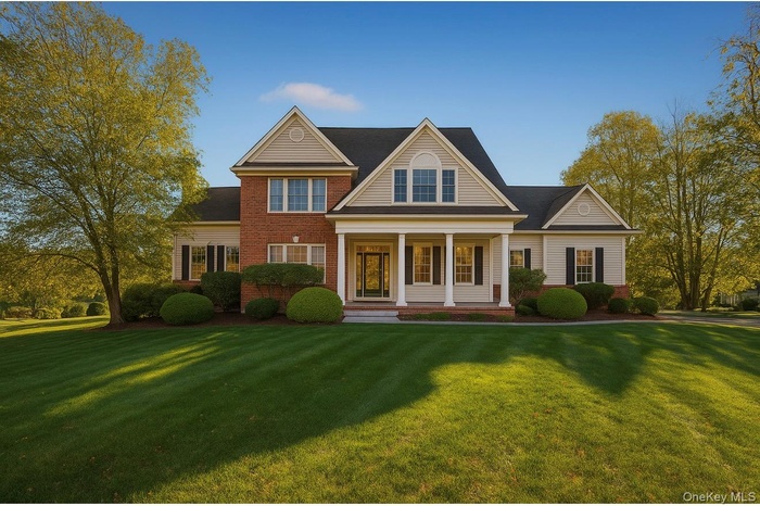 View of front of house with a porch, a front lawn, brick siding, and roof with shingles