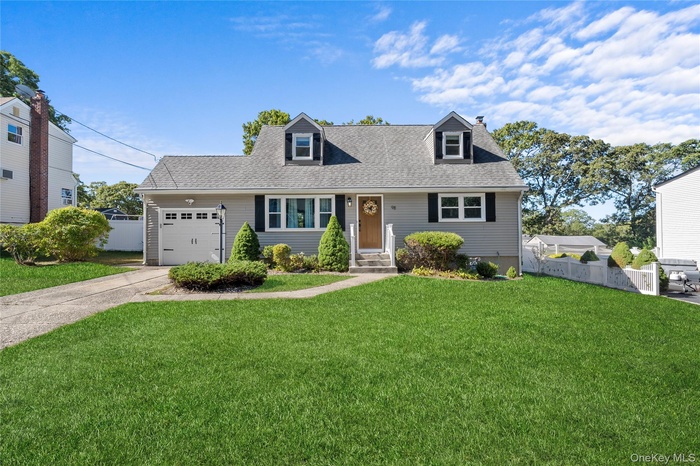 Cape cod-style house with an attached garage, driveway, a shingled roof, and a chimney