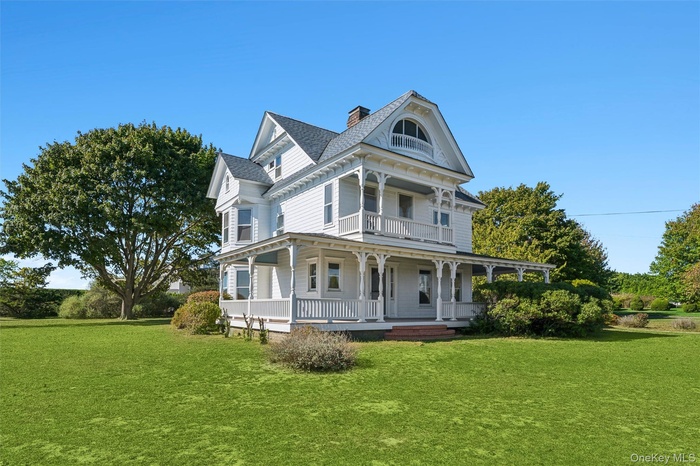 Victorian house featuring a front yard, a porch, a chimney, and roof with shingles