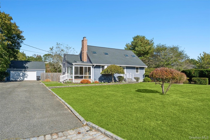 View of front of property with an outdoor structure, a chimney, a garage, a sunroom, and entry steps