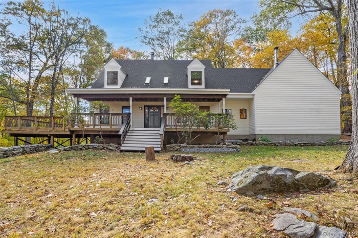 Rear view of house with a porch, roof with shingles, and a lawn