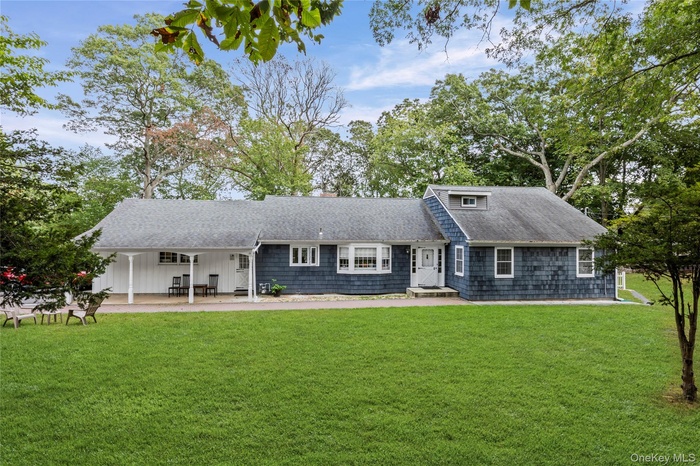 View of front of property with a front yard and a shingled roof