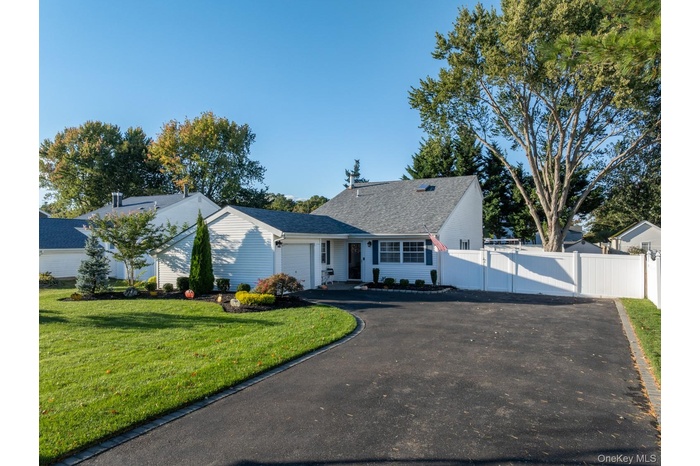 View of front of property featuring asphalt driveway, an attached garage, and a gate