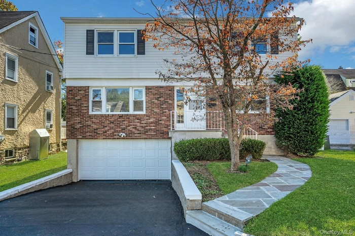 Colonial house featuring brick siding, a front yard, driveway, and a garage