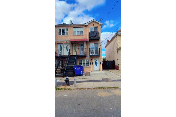 View of front of house with brick siding, a balcony, and stairway