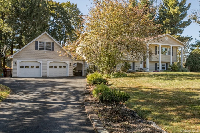 View of front of home featuring driveway, a front yard, and a porch
