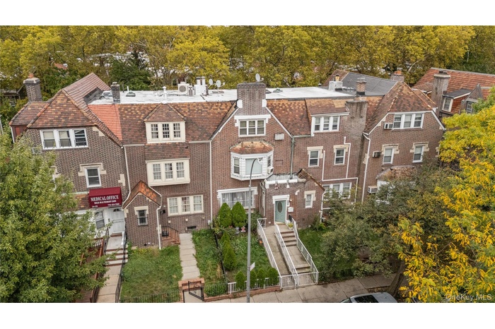 View of front of house featuring a chimney, brick siding, and view of wooded area