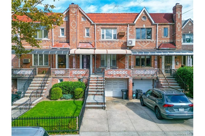 View of front facade featuring stairway, an attached garage, driveway, and brick siding