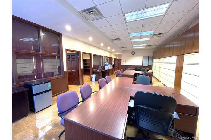 Office space with a drop ceiling, wooden walls, and wainscoting