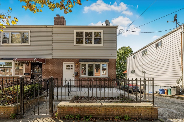 View of front of house with brick siding, a fenced front yard, a gate, and a chimney