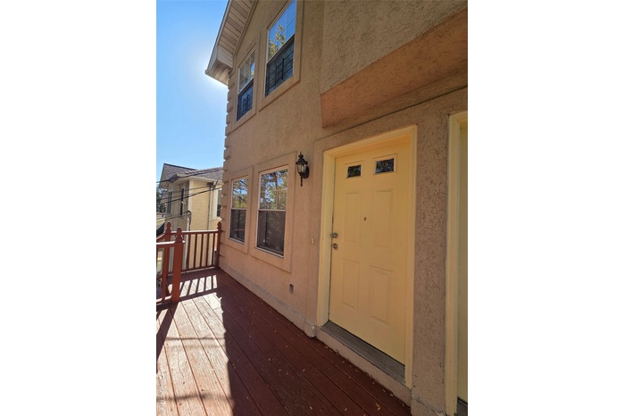 View of exterior entry featuring stucco siding and a deck
