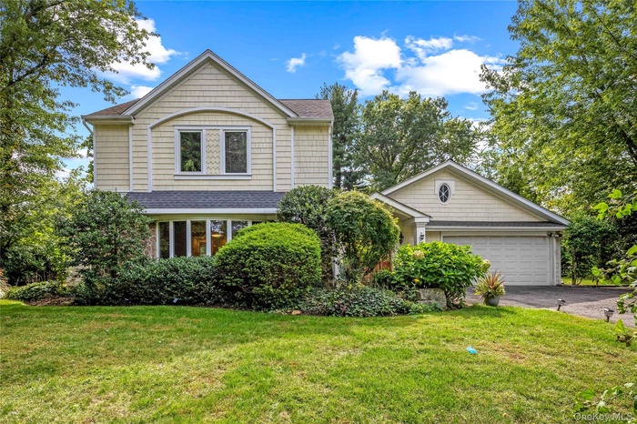 View of front of property featuring a front yard, asphalt driveway, and roof with shingles