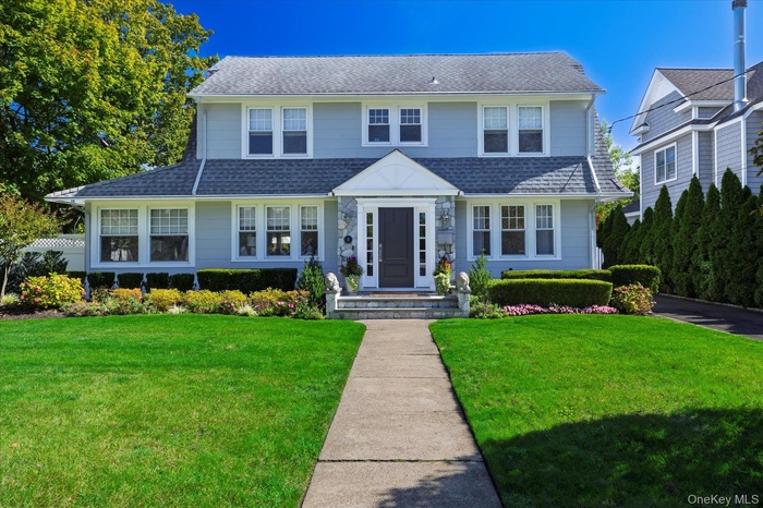 View of front of home with a front lawn and roof with shingles