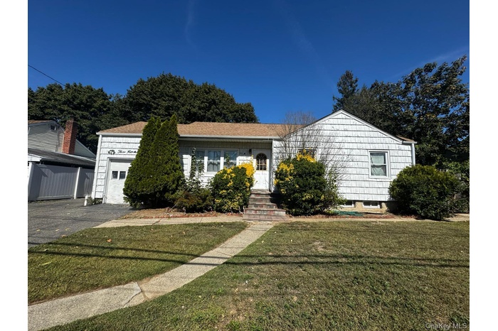 Ranch-style home featuring a front lawn and a garage
