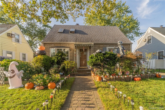 View of front of home featuring stone siding and roof with shingles