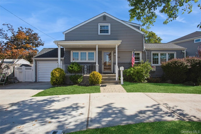 Traditional-style house featuring a porch, roof with shingles, concrete driveway, and brick siding