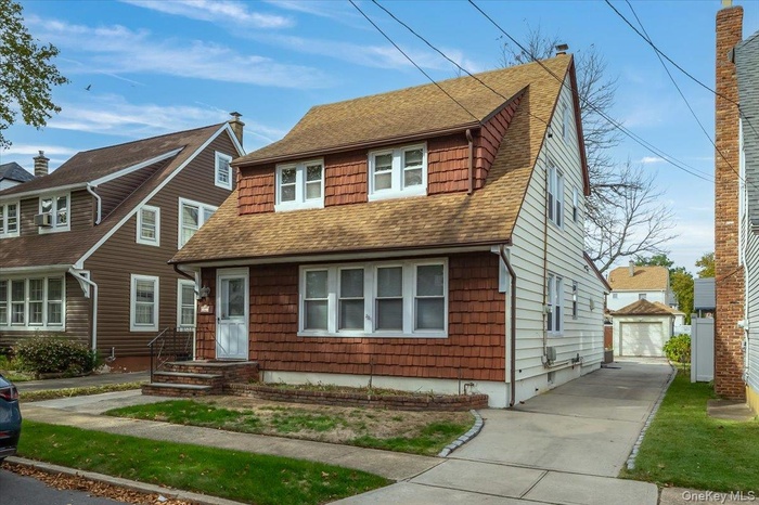 View of front of property featuring roof with shingles, an outbuilding, a chimney, and a detached garage