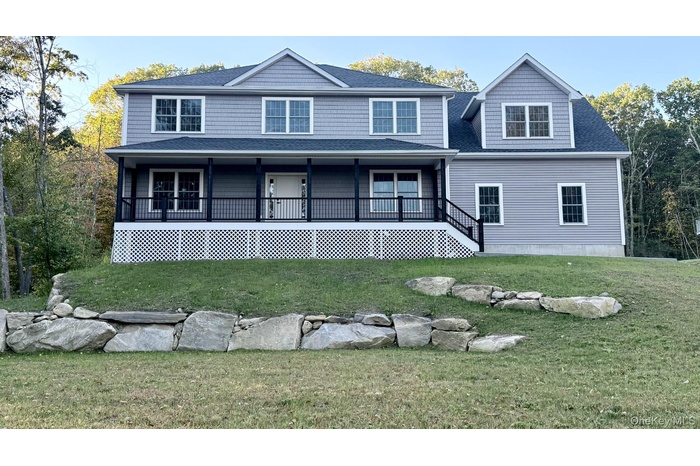 View of front of home with a shingled roof, covered porch, and a front yard