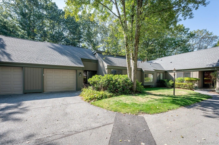 View of front of property with a shingled roof, a front lawn, an attached garage, and driveway