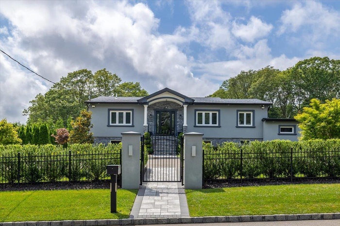 Ranch-style home featuring stone siding, stucco siding, a fenced front yard, and a gate