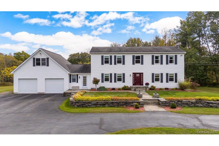 Colonial-style house featuring a front lawn, asphalt driveway, and a garage