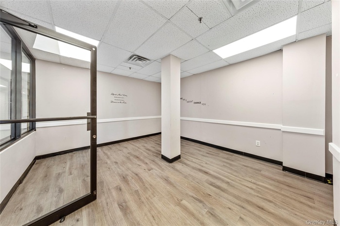 Empty room featuring a drop ceiling, wood finished floors, and baseboards