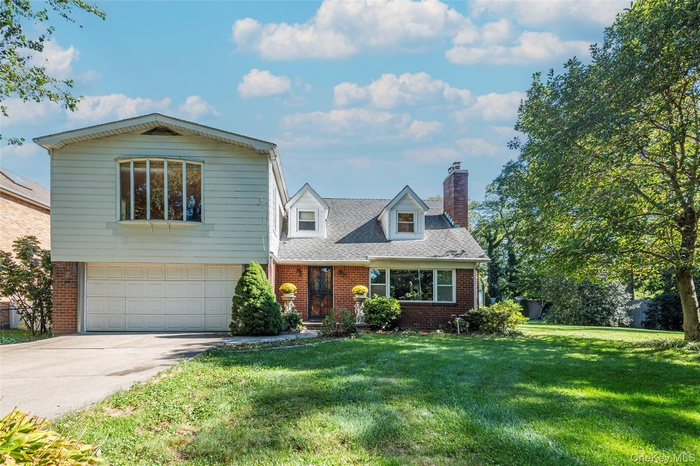 View of front of house featuring brick siding, a front yard, driveway, and a garage