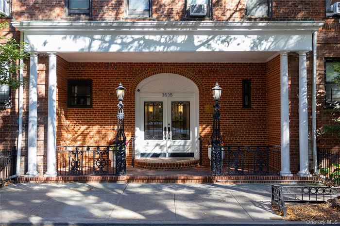 Entrance to property featuring a porch, brick siding, and french doors